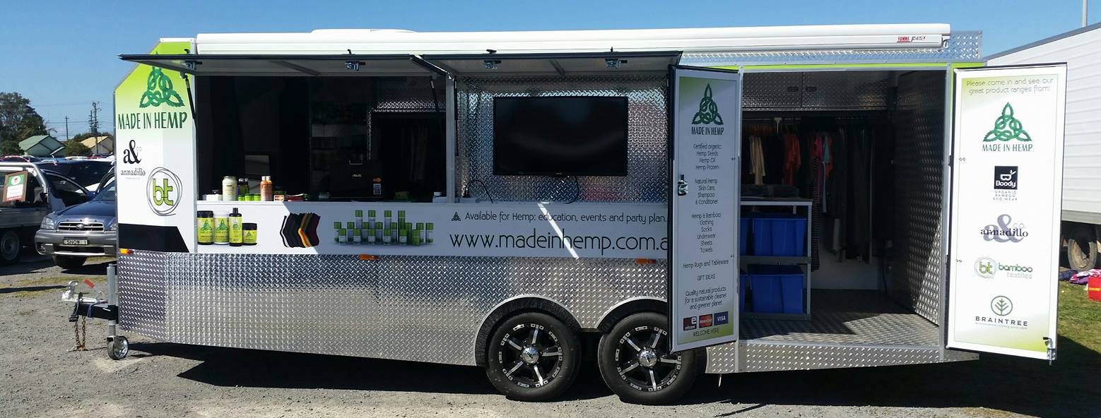 Custom Made In Hemp market trailer opened up at an outdoor market with awning, product displays and clothing racks
